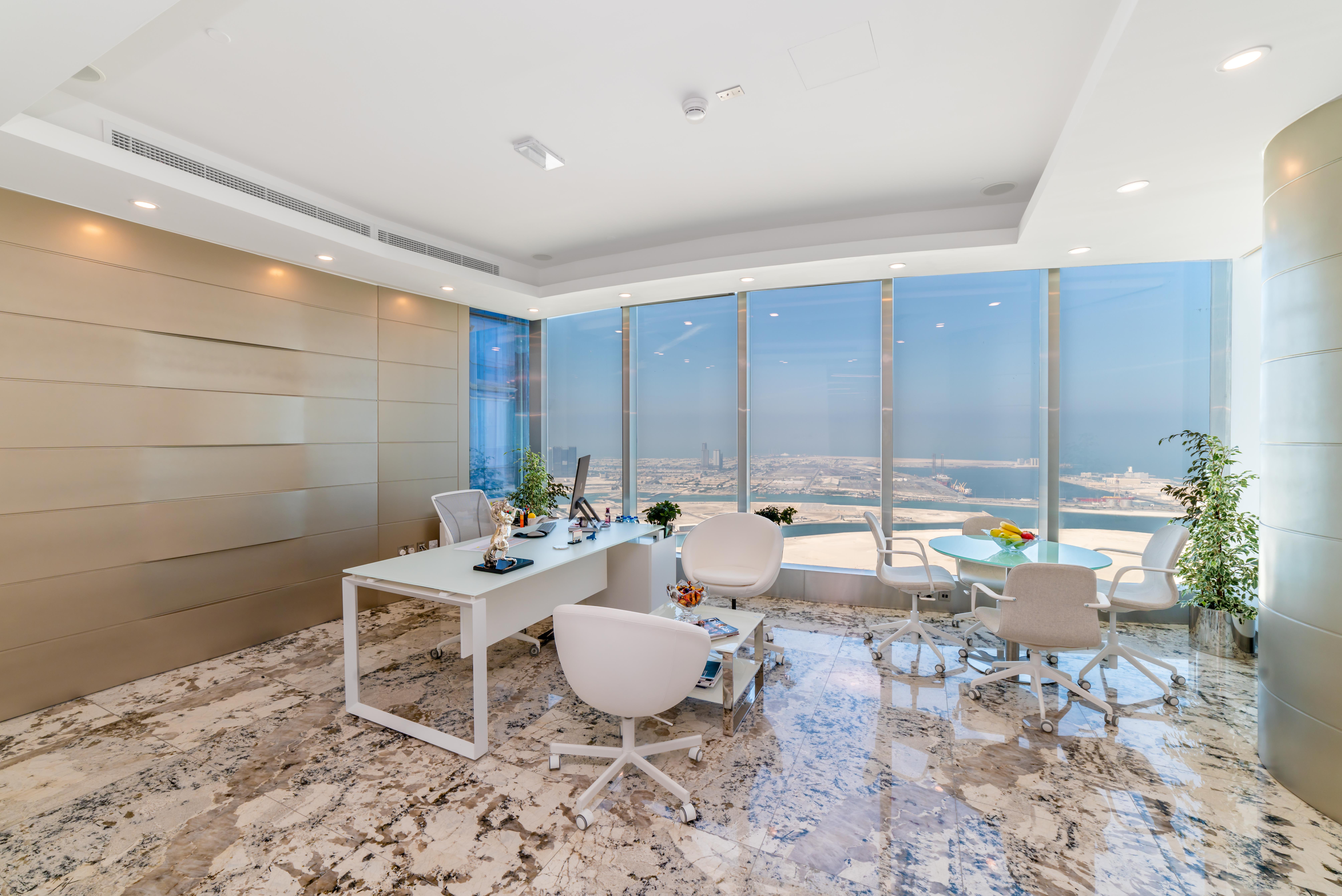After view of the completed Addax Tower corporate office with desks, seating, and Abu Dhabi views.